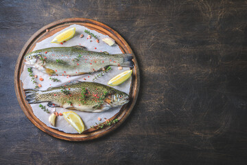 Obraz na płótnie Canvas two raw rainbow trouts on paper with thyme and lemon. Fish trout. Top view. Free space for your text.