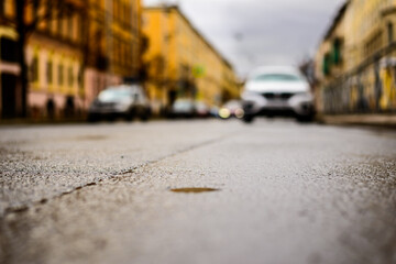 Rainy day in the big city, the headlights of the approaching car. Close up view from the asphalt level