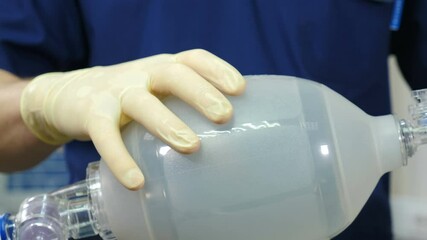 Anesthesiologist with resuscitation breathing bag or Ambu bag in hands. Life saving concept. rescue patients in emergency. Mask for artificial lungs ventilation. Breathing bag with valve inflates and