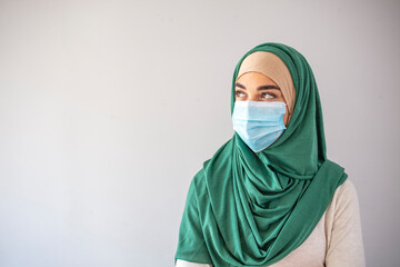 Muslim girl wearing surgical mask for protection. Hijab woman take a mask. Beautiful Arab young woman with disposable face mask. Protection versus viruses and infection.