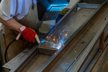 Man welding steel frames in a forgery and metal works workshop