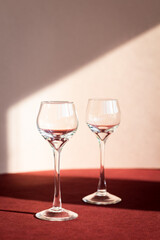 two empty liqueur glasses with long stems, light and shadow on the background, glassware for alcohol drink