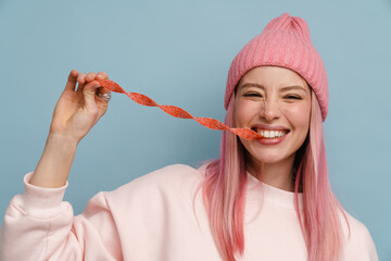 Young white woman with pink hair smiling and eating strip candy