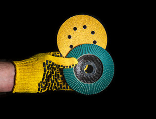 Builder hand in glove keeps or gives abrasive tools close up on isolated black background. The idea of starting a successful work. Free advertising space