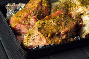 Raw meat beef and chicken legs on a baking sheet are prepared for baking in the oven. The national meat dish is prepared on the eve of the holidays