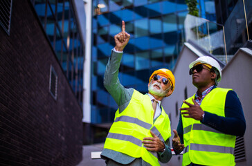 Mature engineer discussing the structure of the building with architects colleague at construction site.