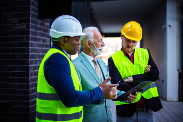 Fototapeta premium The construction site boss has a conversation with the architects. Focus is on background.