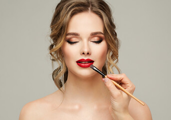 Make up Artist apply Red Lipstick. Beauty Woman Model put on Lip Gloss. Close up Portrait of...