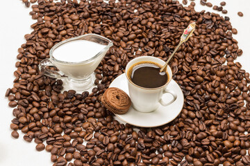 White cup of coffee with froth. Chocolate chip cookies on saucer