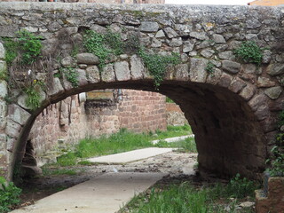 puente medieval construido en piedra negra, con arco dovelado, en la villa de prades, tarragona, españa, europa 