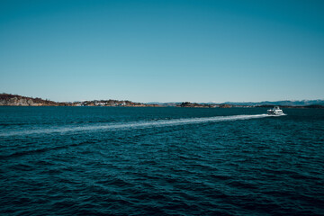 Beautiful landscape of cold North sea and island with small houses. Ferry boat in the sea. Shiny winter day in Norway.