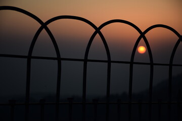 Orange sun isolated on orange background behind the iron gate. Sunset, Selective focus, Selective Focus On Subject, Background Blur