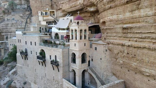 Aerial Shot Of Bell Tower At Saint George Monastery Against Rocky Cliff, Drone Flying Backward - West Bank, Israel