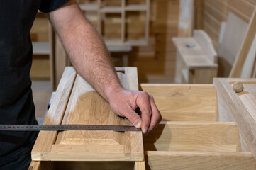 master carpenter measures the cabinet door with a ruler. Production of handmade wooden furniture. Selective focus