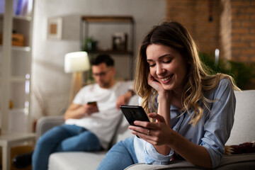 Happy young woman using the phone at home. Excited woman enjoying in the living room...