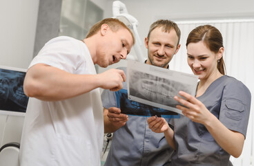 A group of friendly dentists are discussing the x-ray image of the teeth in the office of a modern dental clinic