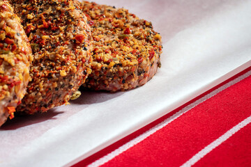 Hot flavor grill steak burgers on white cooking paper and butcher red and white stripe apron. Grinned meat with herbs and spices for summer barbeque. Meat industry product