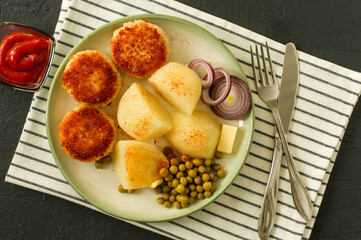 Top view of chicken breaded roasted cutlets with boiled potato and germinated green pea served with onion and ketchup.
