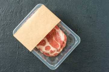 Raw marbled pork steak in vacuum packaging on black background, top view, logo mockup for design