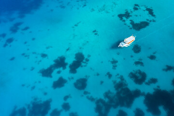 Fototapeta na wymiar Aerial view of a boat in the blue sea. Yachting, luxury vacation at sea.