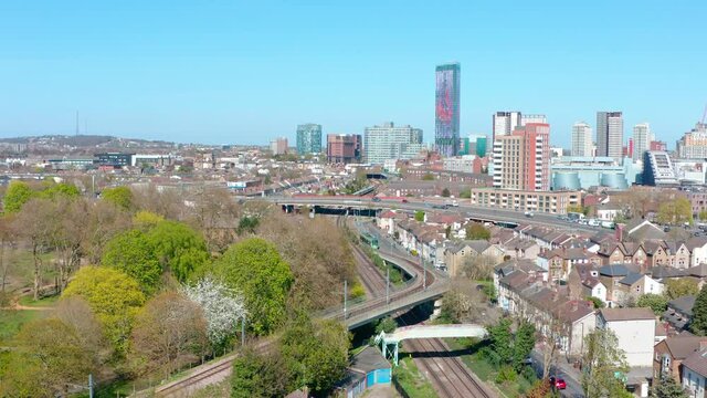 Drone shot towards central Croydon passing over green tram