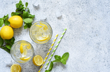 Cold lemonade with lemon, mint and ice on a concrete background. - obrazy, fototapety, plakaty