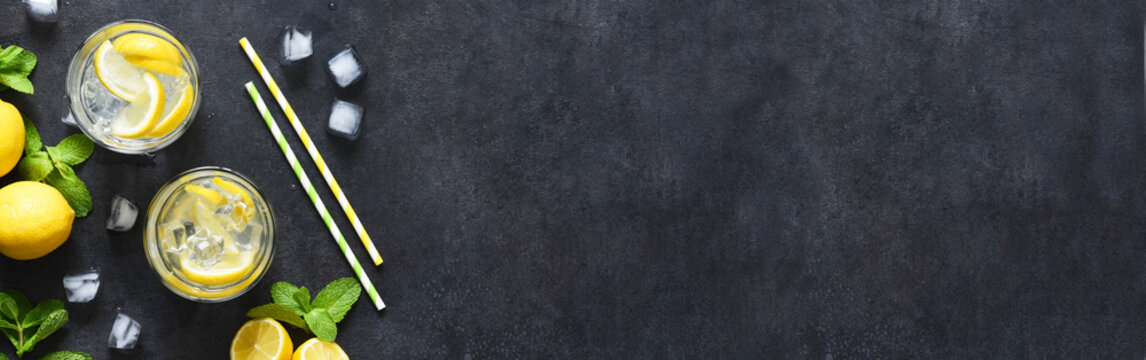 Cold lemonade with mint and ice on a black concrete background, top view.