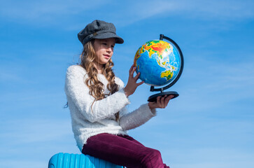 cheerful child choose destination place on globe. stylish kid ready for trip.