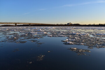 Evening spring landscape. View from the river bank on the ice drift at sunset.