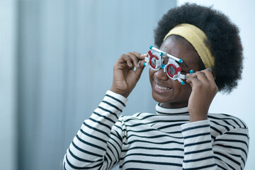 African girl during optic test, holding trial frame for checking to test her vision, selective focus