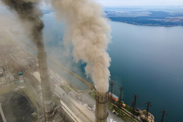 Aerial view of coal power plant high pipes with black smoke moving up polluting atmosphere.