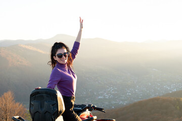 Happy female driver enjoying offroad riding on ATV quad motorbike in autumn mountains at sunset.