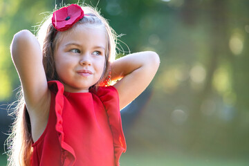 Portrait of happy pretty child girl smiling outdoors enjoying warm sunny summer day.