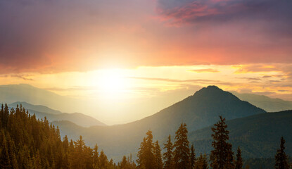Obraz premium Sunset landscape of high mountain peaks under vibrant colorful evening sky.