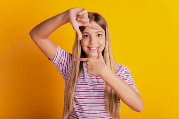 Beautiful happy girl make photo frame with hands isolated pink background