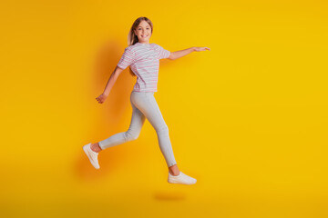 Fototapeta na wymiar Cheerful girl jumping running isolated over yellow background