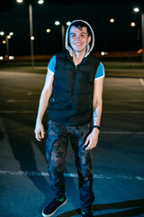 A young man in the parking lot at night amid the lanterns