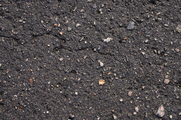 Abstract background of black wet asphalt with inclusions of pebbles