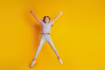 Fototapeta na wymiar Cheerful little schoolchild jumping high isolated yellow background