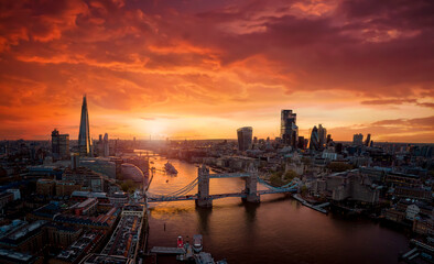 Aerial view of colorful sunset behind the modern skyline of London, United Kingdom, along the Thames river with Tower Bridge and skyscrapers of the City
