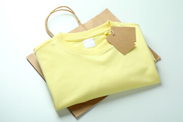Sweatshirt with tags and bag on white background