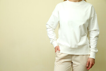 Young woman in white sweatshirt against beige background