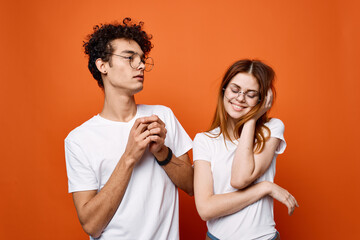 young couple in white t-shirts fun emotions orange background