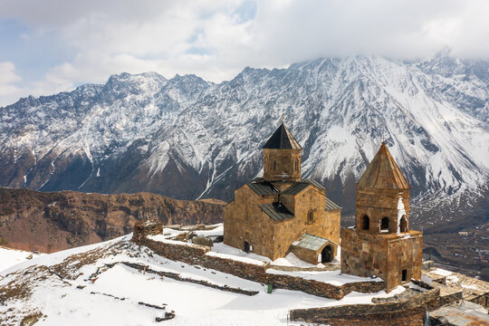 Scenic mountainous landscape with medieval Gergeti Trinity Church and belfry on background with snow covered Mount Kazbegi on spring day, Georgia.