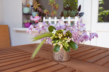 Lovely bouquet of wisteria on a wooden table on a balcony. Fells like summer. Succulents at background.