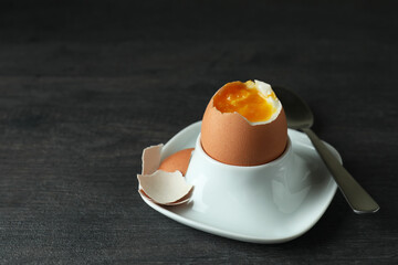 Concept of tasty breakfast with boiled egg on dark wooden table