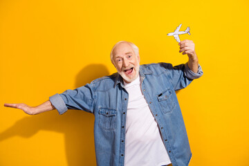 Photo portrait of elder man showing paper plane dreaming about trip on lockdown isolated bright yellow color background