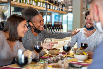 Young afro american man having fun with friends at restaurant, group of people having a party after been vaccinated, happiness for the end of pandemic period