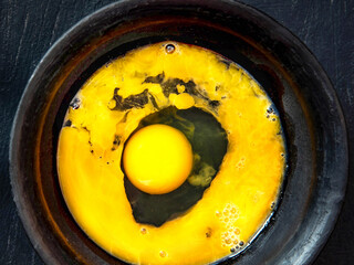 Beaten egg yolks in a bowl on a dark background