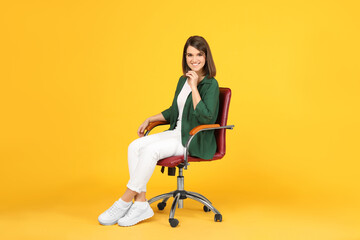 Young woman sitting in comfortable office chair on yellow background